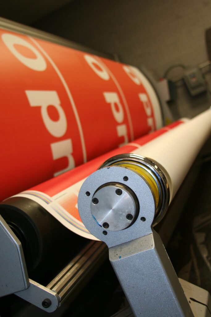 Close-up of an orange banner with white text being printed